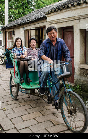 Randonnée cyclo-pousse tour chauffeur de taxi de l'eau village de Tongli, Chine. Banque D'Images