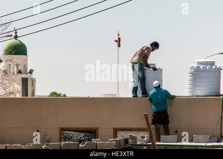 Oman Salalah 17.10.2016 Les personnes travaillant en face de la tour de la mosquée dans la région de Dhofar ubar drapeau Oman Banque D'Images