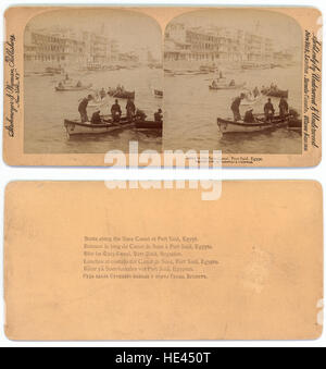 Cette photographie vintage représente des bateaux dans le canal de Suez près de Port-Saïd, en Égypte, un point crucial du commerce maritime mondial. La photographie capture l’importance historique de cette voie navigable, ainsi que les monuments architecturaux du passé égyptien. Banque D'Images