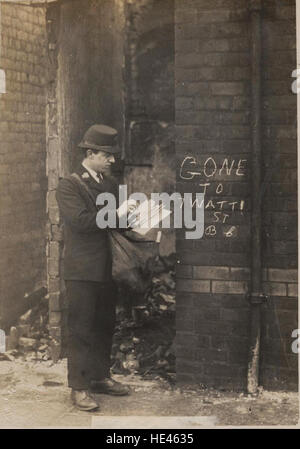 Une image historique des années 1920, montrant un facteur livrant le courrier dans un uniforme, avec un sac de lettres. La scène capture le service postal du début du XXe siècle, mettant en évidence des éléments tels que le mur de briques et le marquage d'adresse à la craie. Banque D'Images