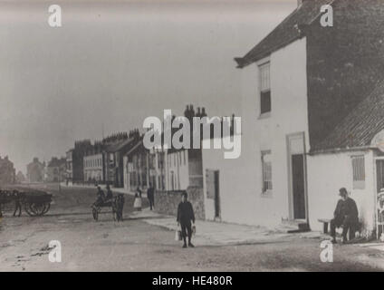 Cette photographie historique capture une scène dans le comté de Durham, Hartlepool, mettant en scène un vieil homme et un garçon avec une charrette, illustrant une époque révolue. L'image reflète la vie rurale et la simplicité de la vie dans les rues de Seaton Carew. Banque D'Images