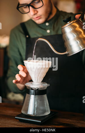 Garçon verse de l'eau bouillie chaude dans un pot de café Banque D'Images