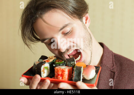 L'homme d'essayer de manger des sushis set sans les mains. Banque D'Images