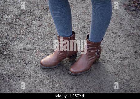 Les jambes de la femme dans des bottes de cuir dans le parc après la pluie Banque D'Images