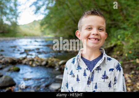 Jeune garçon posant pour un portrait de vie en plein air le long des rives de la rivière McKenzie dans l'Oregon. Banque D'Images