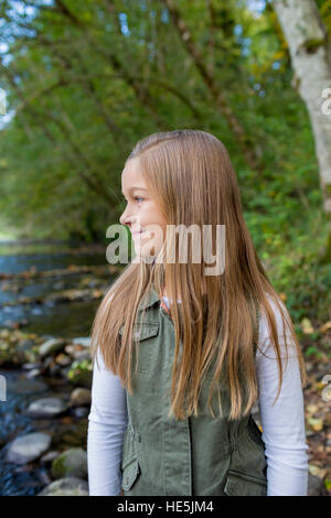 Jeune fille dans un gilet vert posant pour un portrait de vie en plein air le long des rives de la rivière McKenzie dans l'Oregon. Banque D'Images