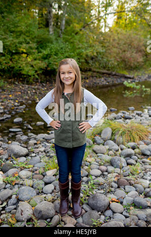 Jeune fille dans un gilet vert posant pour un portrait de vie en plein air le long des rives de la rivière McKenzie dans l'Oregon. Banque D'Images