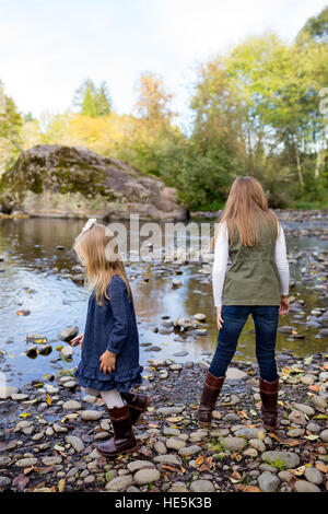 Frères et sœurs jeter des pierres dans la rivière McKenzie ensemble dans le style de photo de l'enfant s'amusant à jouer. Banque D'Images