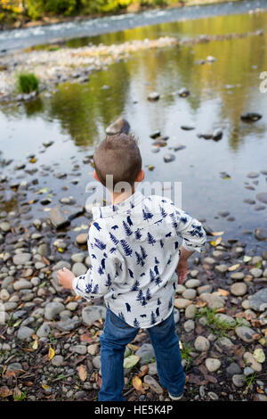 Frères et sœurs jeter des pierres dans la rivière McKenzie ensemble dans le style de photo de l'enfant s'amusant à jouer. Banque D'Images