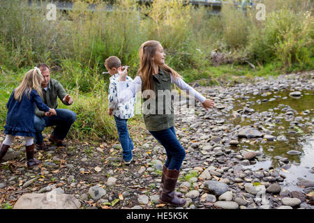 Frères et sœurs jeter des pierres dans la rivière McKenzie ensemble dans le style de photo de l'enfant s'amusant à jouer. Banque D'Images