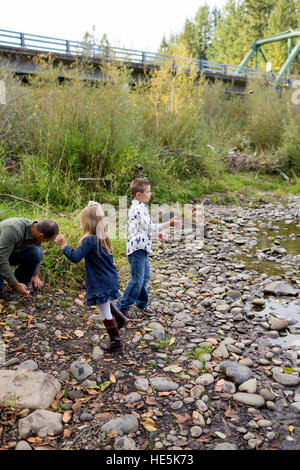 Frères et sœurs jeter des pierres dans la rivière McKenzie ensemble dans le style de photo de l'enfant s'amusant à jouer. Banque D'Images