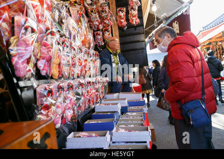 Un homme regarde une Hagoita traditionnels (Battledores) sur l'affichage pendant l'Hagoita-Ichi fair au Temple Sensoji à Asakusa le 17 décembre 2016, Tokyo, Japon. Trouve son origine dans la période Edo la foire annuelle Hagoita-Ichi (Battledore Fair) à Asakusa vend battledores décorées pour bonne chance à charmes et ornement. L'avant de l'hagoita est illustré avec de célèbres acteurs de Kabuki, anime caractères célébrités et vedettes de l'année. © Rodrigo Reyes Marin/AFLO/Alamy Live News Banque D'Images