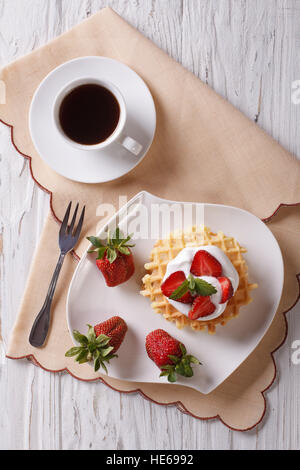 Gaufres aux fraises, de la crème et du café sur une table verticale Vue de dessus. Banque D'Images