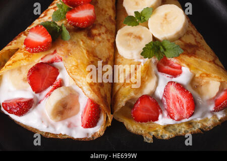 De délicieuses crêpes aux fraises, bananes et crème close-up horizontale. Banque D'Images