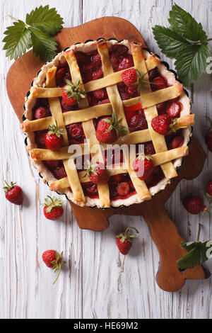 Tarte aux fraises faite maison et de baies fraîches dans un plat allant au four, sur la table. vertical Vue de dessus, rustique Banque D'Images