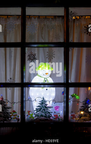 La lumière de Noël Bonhomme de neige décoration dans une fenêtre de la chambre. Deddington, Oxfordshire, Angleterre Banque D'Images