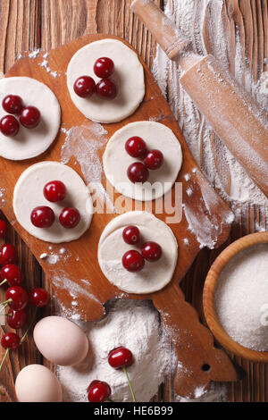 Boulettes de cuisson avec cerises gros plan sur une table en bois vertical Vue de dessus. Banque D'Images