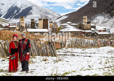 Couple géorgien en costume national en Ushguli, Géorgie. Montagnes du Caucase et les tours médiévales sont vus sur l'arrière-plan. Banque D'Images