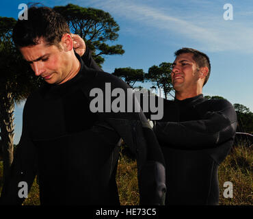 U.S. Air Force Special Tactics aviateurs de la Special Tactics Squadron de formation aider les uns les autres obtenir des combinaisons fermée avant un bénévole marina nettoyage et possibilité de formation sur le militaire Hurlburt Field, 4 novembre 2012. Les aviateurs du Special Tactics Squadron de formation passé leur dimanche de devenir compétent dans des recherches de plongée ainsi que le nettoyage de la partie inférieure de la marina au cours d'une session de formation de plongée de combat de routine. Banque D'Images