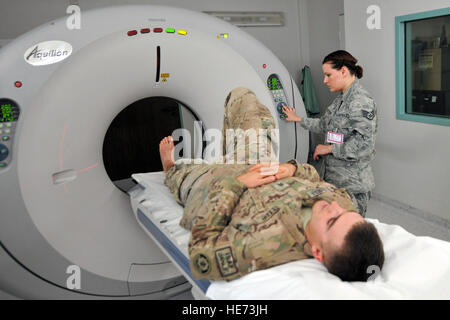 Le sergent de l'armée américaine. Karl Berlinger a une tomodensitométrie scan sur son pied droit avec l'aide (de) Le s.. Brandy Bisson, l'imagerie de diagnostic technicien CAT scan, le 12 février 2014, l'Hôpital régional de Landstuhl, en Allemagne. Berlinger et son unité ont été sur leur chemin de retour à l'aérodrome de Kandahar, en Afghanistan, après une patrouille de périmètre lorsqu'ils ont été frappés par un dispositif explosif, qui a la porte vers l'intérieur des véhicules à l'échelle du claquement Berlinger pied droit. (U.S. Photo Force/Senior Airman Chris Willis) Banque D'Images