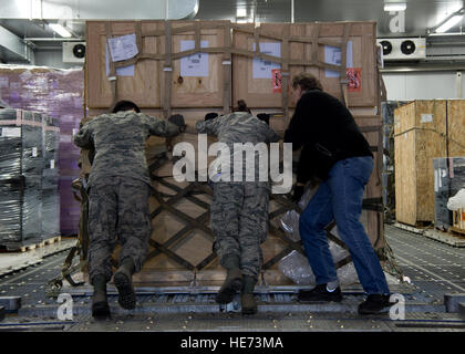 Aviateurs et un Allemand de la 721e Escadron Port Aérien transporter des marchandises en stock, 16 janvier 2015, à la base aérienne de Ramstein, en Allemagne. Le 721e spécial APS gestionnaires sont un groupe formés et agréés pour manipuler des matières dangereuses, les restes humains, matériels frigorifiques, courrier recommandé et de glace ou re-ice fret sensible. Jonathan Stefanko Senior Airman) Banque D'Images