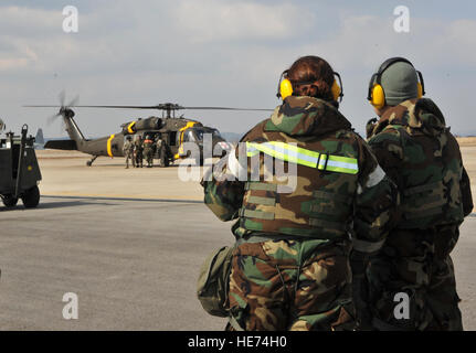 Tech. Le Sgt. Kimberly Cruickshank, 51e Escadron en médecine aérospatiale médecine vol sous-officier responsable, à gauche, et le Capitaine Peter Lee, 51e Escadron dentaire dentiste général, attendre le signal d'approche d'un hélicoptère d'évacuation médicale Black Hawk à partir du 3e Bataillon de soutien général à l'aviation de l'armée américaine Garrison Humphreys, République de Corée, au cours d'une évacuation sanitaire et de poussière dans le cadre du scénario de l'exercice de l'état de préparation opérationnelle Beverly minuit 14-02 à Osan Air Base, République de Corée, le 12 février 2014. Les deux faisaient partie d'une équipe médicale de quatre personnes qui repêche cinq victimes simulées à partir de l'hélicoptère trois débarquements et chargé Banque D'Images