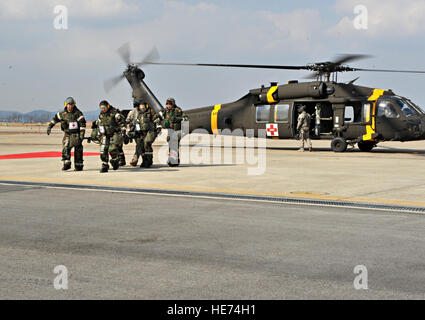 Les membres du 51e Groupe de l'équipe d'intervention médicale sur le terrain et un soldat du 3ème Bataillon de soutien général à l'aviation de l'armée américaine Garrison Humphreys, République de Corée, de transporter une victime simulée à partir d'un hélicoptère d'évacuation médicale Black Hawk en attente d'une ambulance lors d'une évacuation sanitaire et de poussière dans le cadre du scénario de l'exercice de l'état de préparation opérationnelle Beverly minuit 14-02 à Osan Air Base, République de Corée, le 12 février 2014. Les soldats de la 3-2 GSAB pratiqué ramasser des victimes simulées à partir de la simulation de missions de terrain et à leur transport à Osan pour traitement médical. Navigant de première classe Ashley J. Thum) Banque D'Images