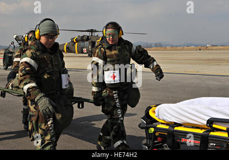 Les membres du 51e Groupe de l'équipe d'intervention médicale sur le terrain portent une victime simulée d'une ambulance en attente pendant une évacuation sanitaire et la poussière-off dans le cadre du scénario de l'exercice de l'état de préparation opérationnelle Beverly minuit 14-02 à Osan Air Base, République de Corée, le 12 février 2014. Au cours d'une opération d'urgence, de l'armée américaine soldats affectés à des unités d'évacuation sanitaire s'effectuer à pied et de poussière porter blessés des troupes terrestres dans les bases locales avec les hôpitaux pour soins médicaux. Navigant de première classe Ashley J. Thum) Banque D'Images