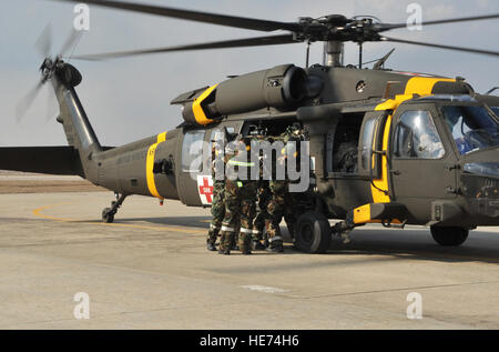 Les membres du 51e Groupe médical de l'aide des soldats du 3e Bataillon de soutien général à l'aviation de l'armée américaine Garrison Humphreys, République de Corée, de décharger une victime simulée à partir d'un hélicoptère d'évacuation médicale Black Hawk lors d'une évacuation sanitaire et de poussière dans le cadre du scénario de l'exercice de l'état de préparation opérationnelle Beverly minuit 14-02 à Osan Air Base, République de Corée, le 12 février 2014. Minerais sont une occasion unique pour le personnel médical de participer à la formation conjointe avec d'autres branches de l'armée, imitant les opérations dans un monde réel de l'engagement. Navigant de première classe Ashley J. Thum) Banque D'Images