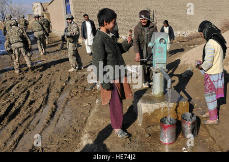 Les membres de la 777th escadron expéditionnaire de boeuf premier et le 755e Escadron des Forces de sécurité expéditionnaire regarder comme des enfants utilisent l'eau fixe récemment bien à un village près de Bagram, en Afghanistan, l'Air le 26 janvier 2013. L'eau revêt une grande importance dans l'Islam, il est considéré comme une bénédiction de Dieu qui donne et entretient la vie, et de purifier l'humanité et la terre. Chris Willis) Senior Airman Banque D'Images