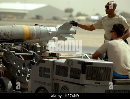 Le sergent de l'US Air Force. Renaldo Richardson, en haut à droite, une bombe GBU-38 guides d'être élevé par un MJ-1B Jammer conduit par le sergent. Robert Corso, afin qu'il puisse être chargés à bord d'un A-10C Thunderbolt II à l'aérodrome de Kandahar, en Afghanistan, le 8 août 2011. Richardson et Corso sont membres de l'équipage d'armes déployés à partir de la 74e Unité de maintenance d'aéronefs, Moody Air Force Base, Ga. Banque D'Images