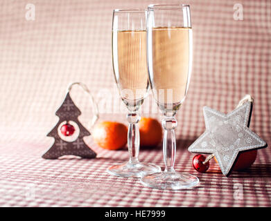 Image de deux wineglasses de champagne en bois décoratif, star et d'arbres et des mandarines sur le fond rouge à carreaux. Style rustique. Banque D'Images