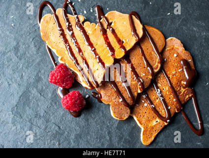 Des crêpes en forme de coeur avec le sirop de chocolat et de framboises sur la Saint-Valentin. Banque D'Images