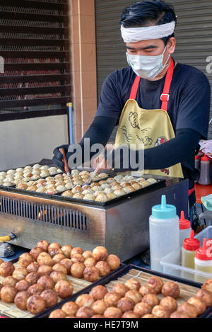 La cuisson des boulettes de Takoyaki chef japonais à un marché alimentaire en plein air festival. Thaïlande S. E. l'Asie. Banque D'Images