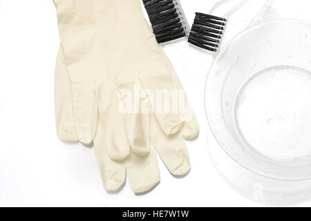 Outils pour la teinture des cheveux se trouvent sur un tableau blanc : gants en caoutchouc, bol, brosse, peigne. Blanc sur blanc. Banque D'Images