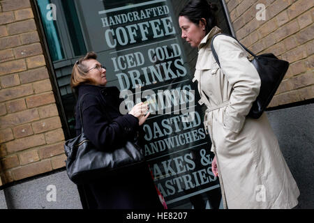 Deux femmes ayant un chat dans une petite alcôve loin de l'agitation d'une rue de Londres occupé Banque D'Images