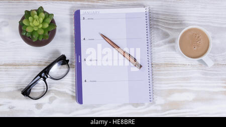 Agenda et stylo avec lunettes de lecture, et des plantes de café crémeux blanc rustique sur desktop Banque D'Images