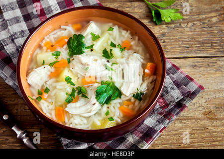 Soupe de poulet aux vermicelles et légumes dans un bol au fond rustique en bois - des repas sains Banque D'Images