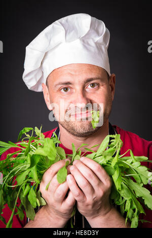 Gros plan du happy chef holding de roquette sur fond noir Banque D'Images