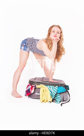 La femme ferme une valise pleine de vêtements, studio Banque D'Images