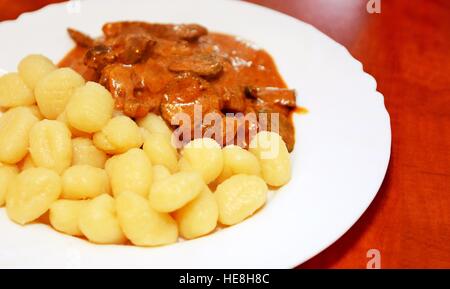 Bœuf Stroganoff avec gnocchi de pommes de terre à l'assiette blanche. Banque D'Images