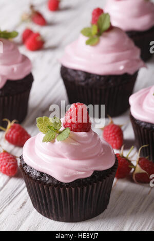 Petits gâteaux au chocolat avec des framboises fraîches sur la table close-up vertical. Banque D'Images