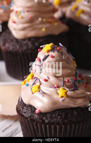 De beaux petits gâteaux au chocolat avec des bonbons saupoudre sur la table verticale de macro. Banque D'Images