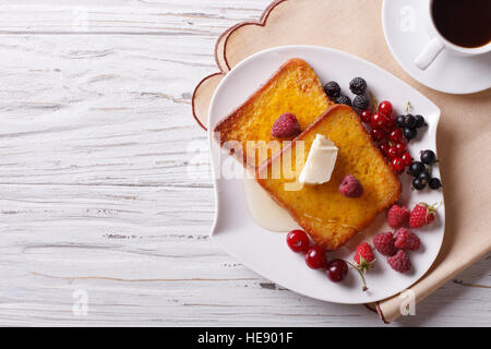 French toast avec du miel et de petits fruits sur une plaque horizontale vue du dessus. Banque D'Images