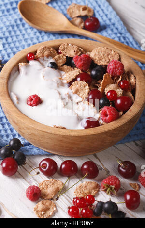 Petit-déjeuner sain : flakes avec du lait et des baies close up dans un bol en bois. La verticale Banque D'Images