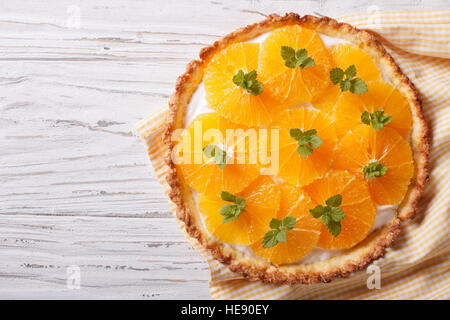 Tarte aux agrumes orange et menthe crème blanc sur la table horizontale vue du dessus. Banque D'Images