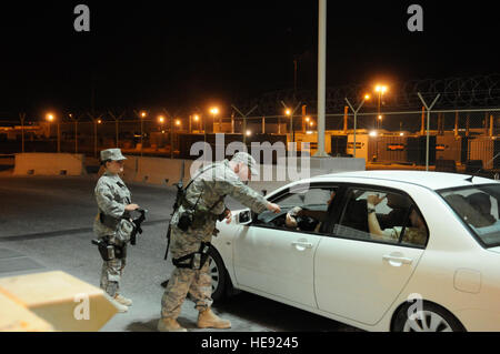 Airman Senior William Baker, 379e Escadron des Forces de sécurité de l'expéditionnaire, examine une identification du conducteur avant d'autoriser le véhicule à travers un point de contrôle, le 21 novembre, à une base aérienne en Asie du Sud-Ouest. Navigant de première classe Kari Kasprzyk, 379 SESF, fournit la sécurité à distance. Les membres des Forces de sécurité de l'Armée de l'air d'écrire et de mettre en œuvre la protection des ressources, les activités de l'ordre et de sécurité pour les partenaires de la coalition et au Commandement central de cette base aérienne. Airman Baker est originaire de Francfort, Allemagne, et est déployée à partir de la Base Aérienne de Spangdahlem, en Allemagne. Airman Kasprzyk est un na Banque D'Images