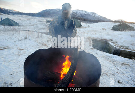 Lieutenant de l'Armée de Holly Rupprecht, attribué à 6e bataillon du génie (Combat) (Airborne), originaire de Sterling, Ill., réchauffe ses mains sur une lumière de l'Arctique au cours de la formation individuelle sur Bulldog Trail, le 6 décembre 2012, au-dessous de zéro. ALIT est l'armée des États-Unis Alaska's programme d'endoctrinement par temps froid. Il donne à tous les soldats, quel que soit leur emploi, la Fondation pour le travail, de former, et de faire la guerre dans certains des environnements les plus rudes au monde. Justin Connaher) Banque D'Images