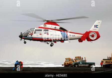 Une Garde côtière canadienne (Islande) / Landhelgisgaeslan Islenska Eurocopter Aerospatiale AS-365N Dauphin 2 (TF-SIF) Recherche et sauvetage (SAR) hélicoptère survole la plage comme il se prépare à livrer l'équipement pour la pêche islandaise, le chalutier BALDVIN THORSTEINSSON, qui s'est échoué sur un banc de sable au large de la côte sud de l'Islande lors du transport d'une très précieuse de captures de 1 500 tonnes de poissons de capelan. Banque D'Images