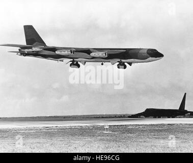 Un B-52 Stratofortress attend d'avion à côté de la piste comme un B-52G des approches pour l'atterrissage après avoir terminé une mission de bombardement sur le Nord du Vietnam au cours de l'opération LINEBACKER. Les avions sont du Commandement aérien stratégique. Banque D'Images